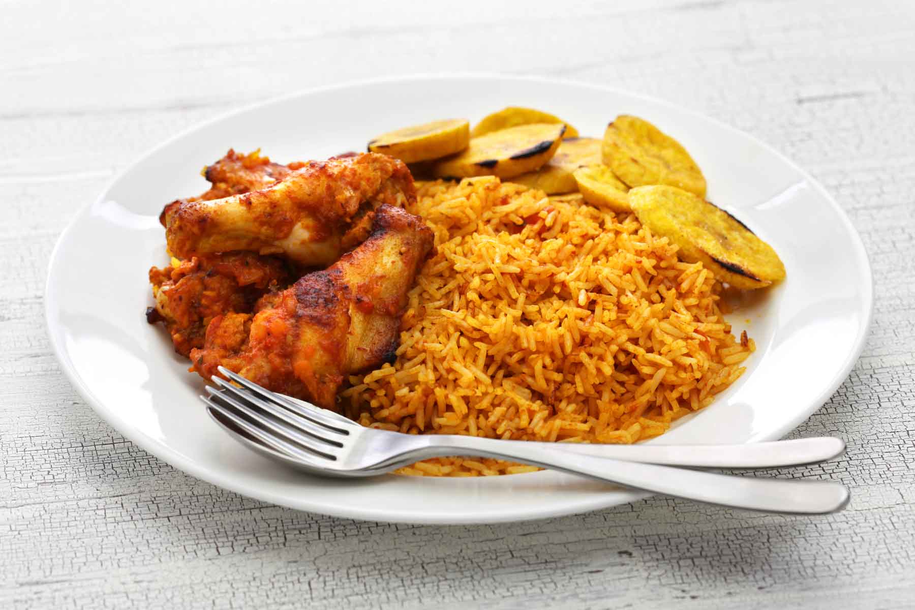 Jollof rice served with plantains and chicken wings